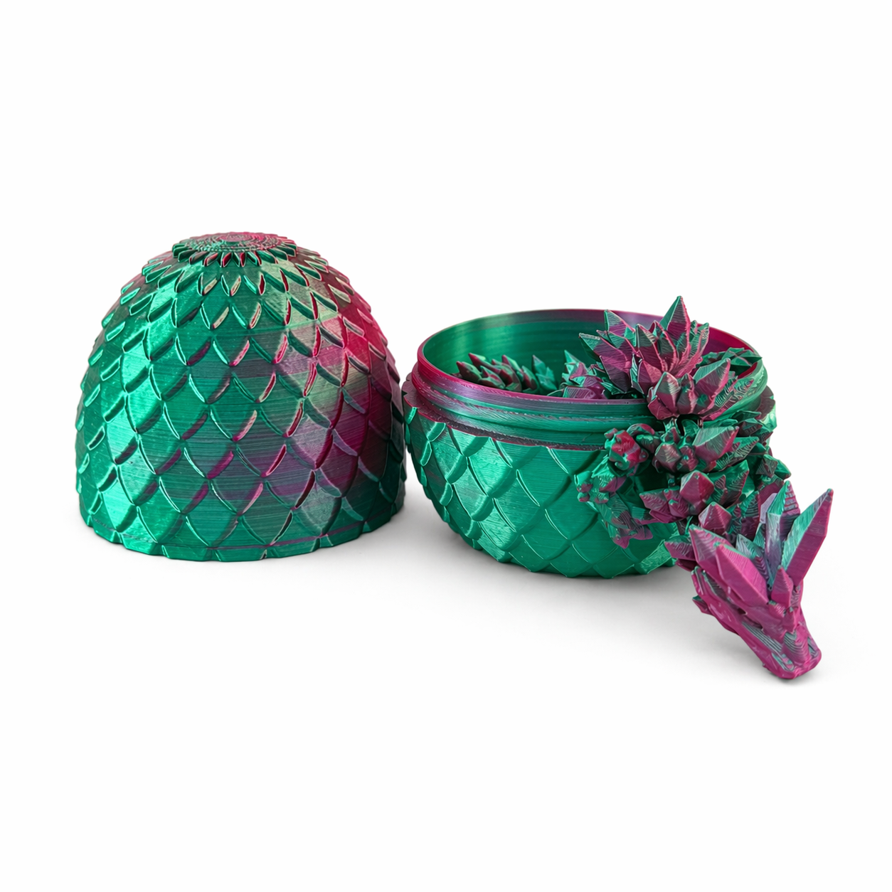 3D printed pink and green articulated dragon emerging from matching dragon egg with lid beside it