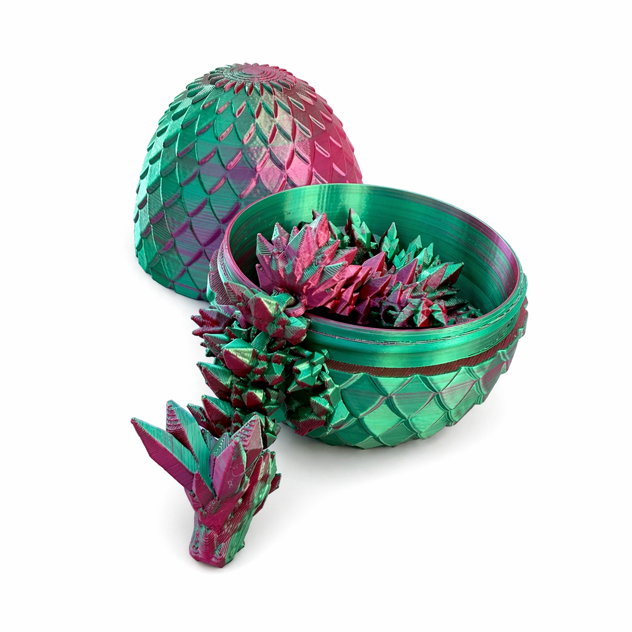 Close-up of articulated 3D printed dragon curled inside pink and green dragon egg showing detailed texture